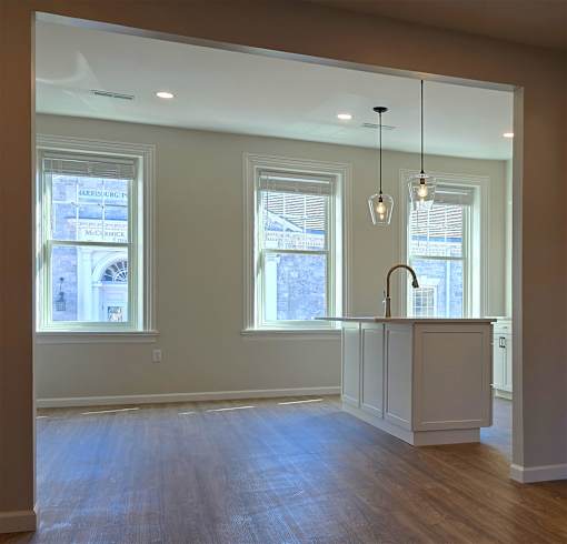A kitchen with a white counter and wooden floors.