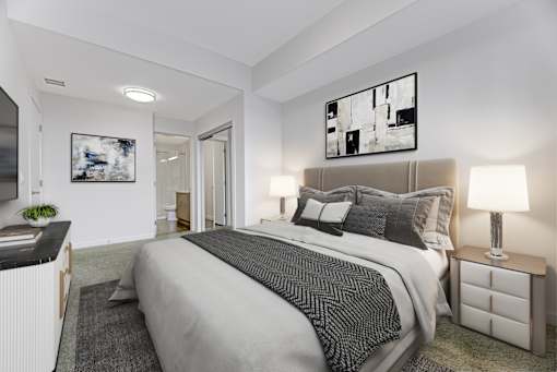 A bedroom with a large bed and a painting on the wall.