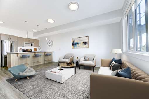 A modern living room with a kitchen area in the background.