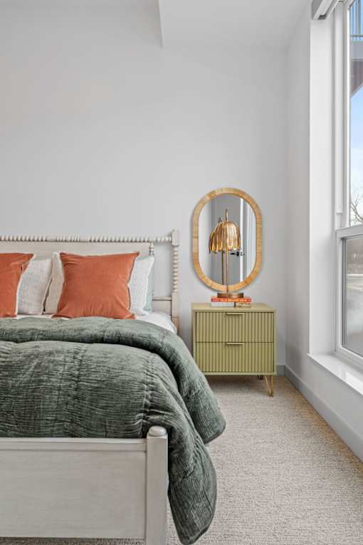 A bedroom with a bed, a dresser, and a mirror.