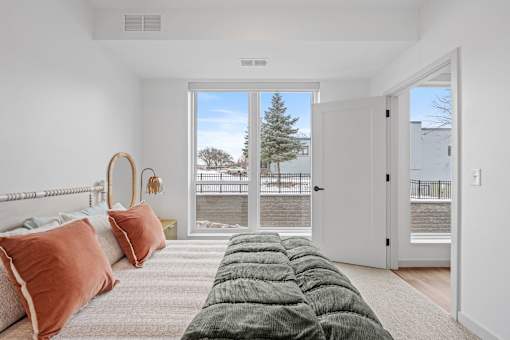 A bedroom with a large bed and a view of the outdoors through a sliding glass door.