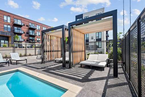 A modern outdoor pool area with a wooden structure and lounge chairs.
