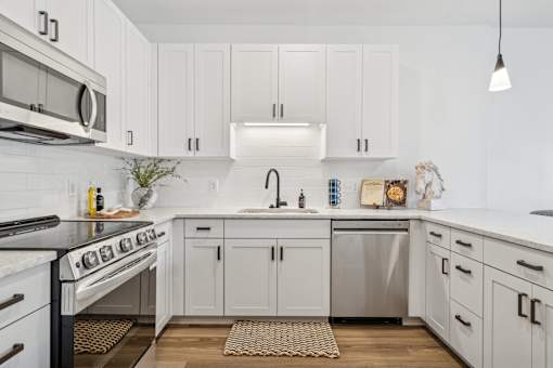 A modern kitchen with white cabinets and stainless steel appliances.