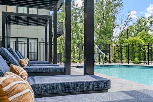 A poolside area with lounge chairs and a building in the background.