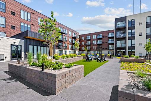 A modern building complex with a landscaped courtyard in the foreground.