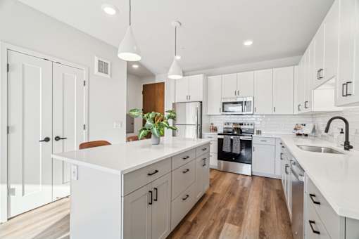 A modern kitchen with white cabinets and a wooden floor.