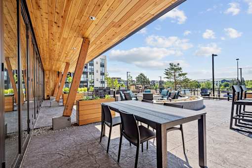 A wooden table with chairs is set up outside on a patio.