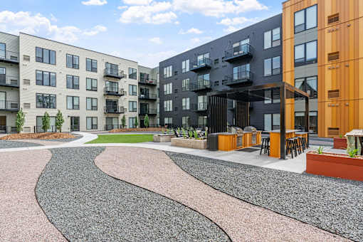 A modern apartment complex with a gravel courtyard in the foreground.