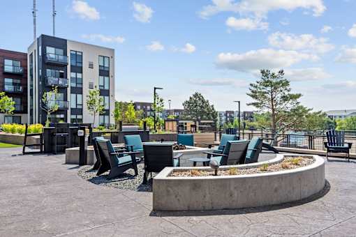 A modern outdoor seating area with a circular fire pit in the center.