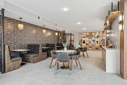 A modern dining area with a patterned wallpaper and a mix of wooden and black chairs.