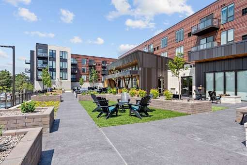 A modern outdoor seating area with black chairs and tables is surrounded by apartment buildings.