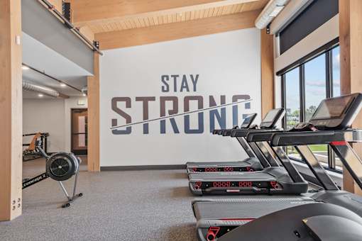 A gym with treadmills and a wall that says "Stay Strong".