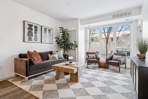 A living room with a black couch, a coffee table, and a rug.