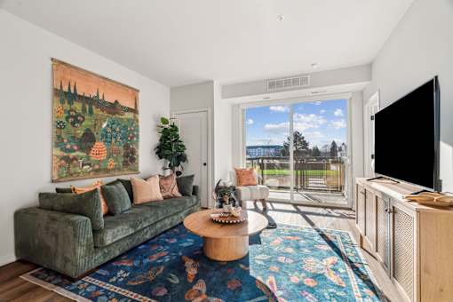 A living room with a green couch and a large painting on the wall.