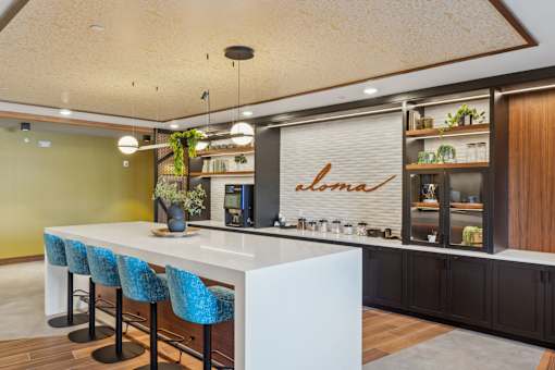 A modern kitchen with a white counter and blue chairs.