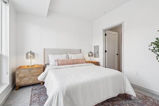 A bedroom with a large bed and a wooden chest of drawers.
