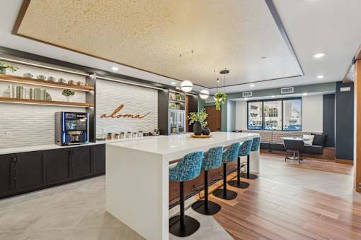 A modern kitchen with a white counter and blue chairs.