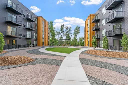A modern apartment complex with a central walkway and landscaped gardens.