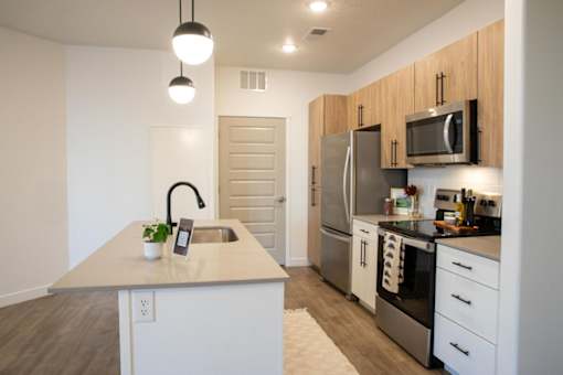 A kitchen with a sink, refrigerator, and oven at Parc on 5th Apartments & Townhomes