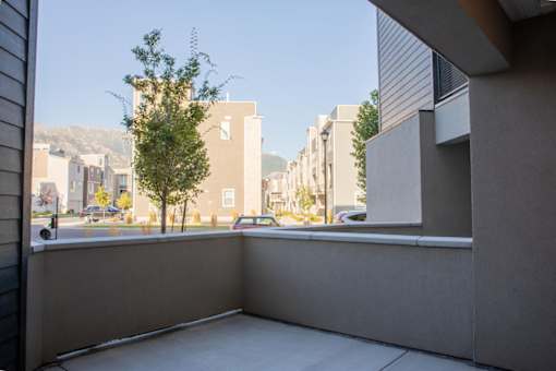 A balcony with a view of a street and buildings from Parc on 5th Apartments & Townhomes