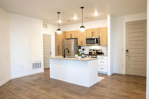 A kitchen with wooden cabinets and a white island at Parc on 5th Apartments & Townhomes