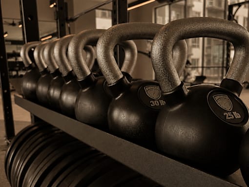 A rack of black kettlebells with 30 and 25 lb weights.