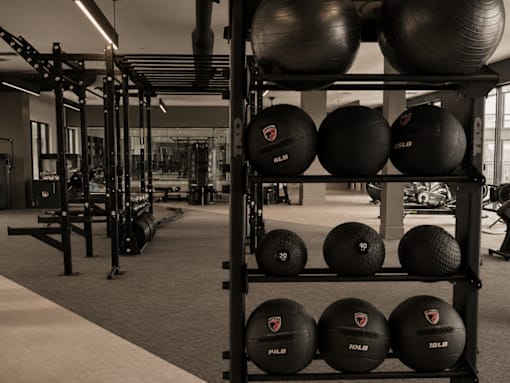 A gym with a rack of black exercise balls.