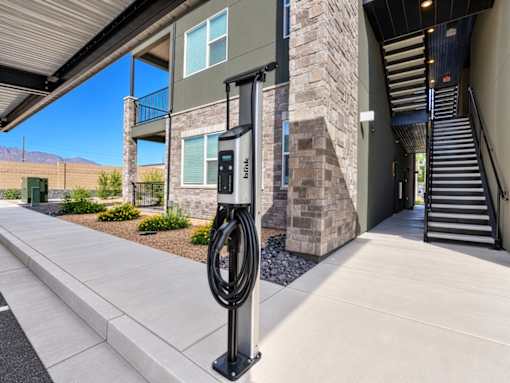 A parking meter is on the sidewalk outside a building.