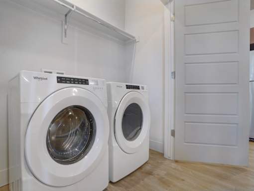 Two white front loading washing machines in a laundry room.