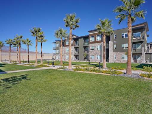 A row of palm trees in front of a building.