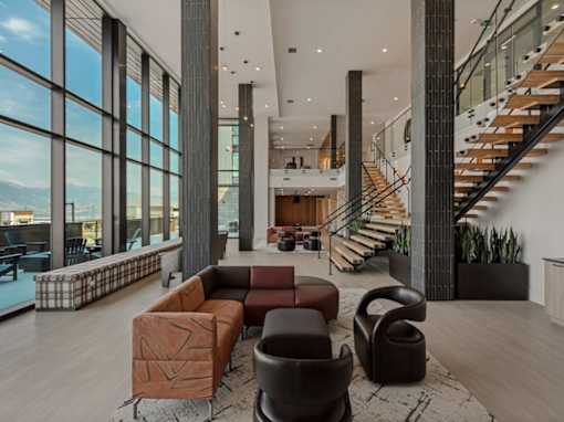 A modern living room with a staircase and a large window.