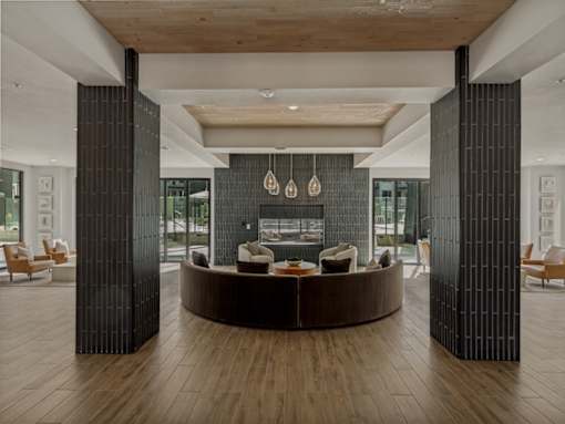 A modern living room with a curved wooden coffee table and a dark grey wall.