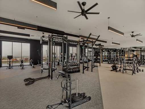A spacious gym with a variety of equipment and a ceiling fan.