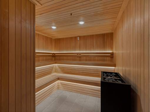 A wooden sauna with benches and a light on the ceiling.