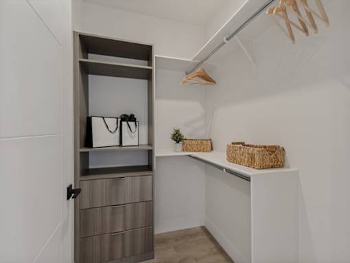 A white closet with a shelf and a basket on it.