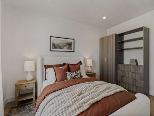 A bedroom with a large bed and a wooden nightstand.