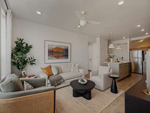 A living room with a grey couch, a black coffee table, and a painting of a desert landscape on the wall.