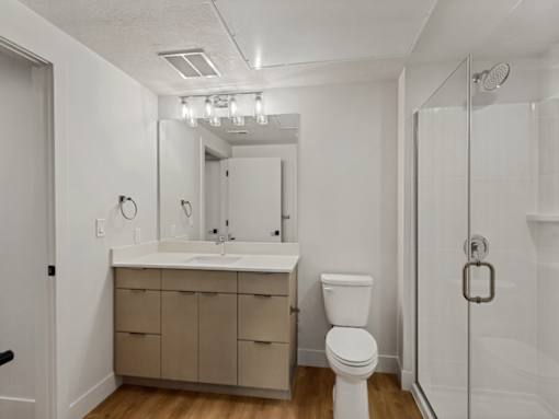 A white bathroom with a toilet, sink, and mirror.