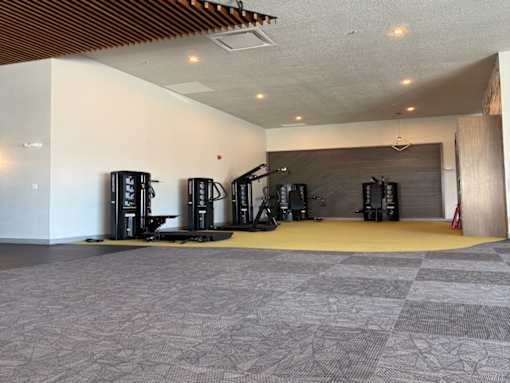 A room with a grey carpet and a wooden ceiling with a few black objects on the floor.