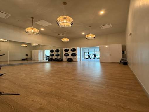 A spacious room with wooden floors and a large mirror on the wall.