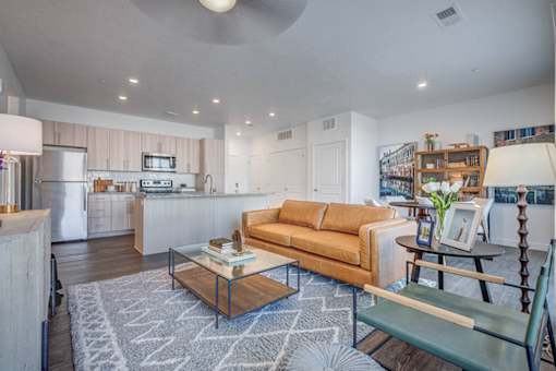 A modern living room with a sofa, coffee table, and a kitchen area in the background.