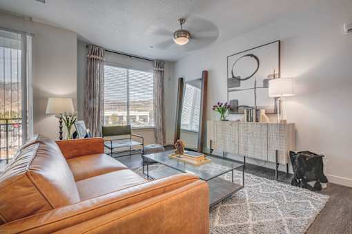 A living room with a brown leather couch and a glass coffee table.