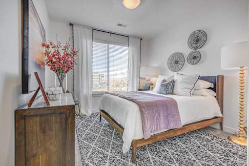 A bedroom with a large bed and a wooden dresser.