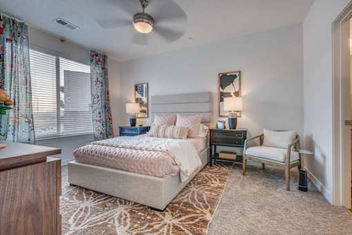 A bedroom with a large bed and a ceiling fan.