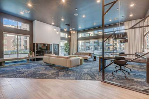A modern living room with a large sofa and a glass wall.