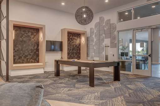 A modern living room with a grey carpet and a wooden table.