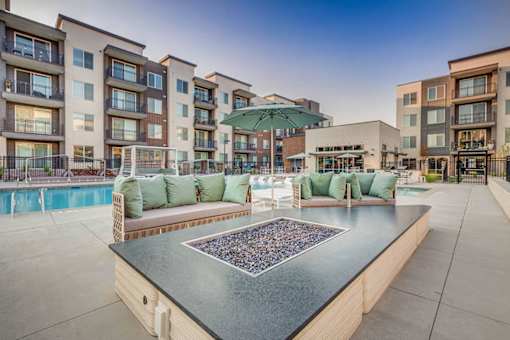 A poolside area with a hot tub and seating area in front of apartment buildings.