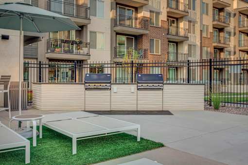 A white table and chairs are set up on a green lawn in front of a building.
