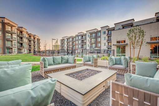A modern outdoor seating area with a fire pit in the center.