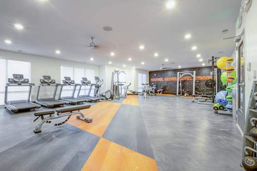 A gym with a variety of equipment including treadmills, weights, and exercise machines.